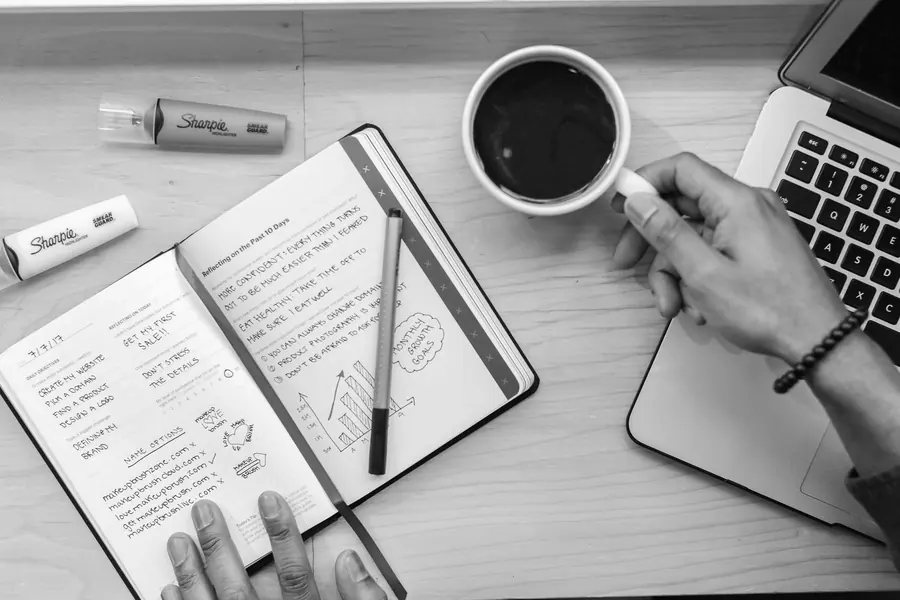 Carnet ouvert, surligneurs et café sur un bureau