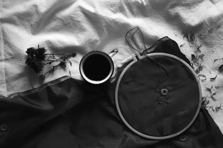 Cercle à broder avec du tissu brodé, à côté d’un café